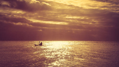 Silhouette person in sea against sky during sunset