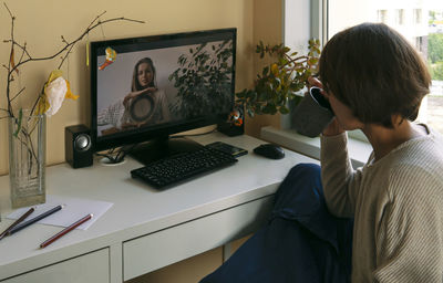 Woman video conferencing with friend over computer at home