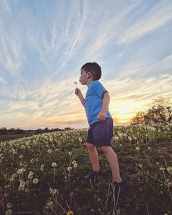 Full length of girl standing on field against sky during sunset