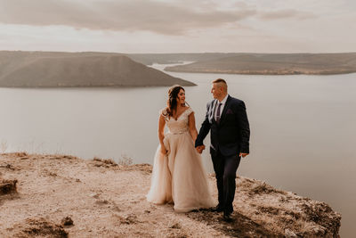 Rear view of couple standing on sand at desert