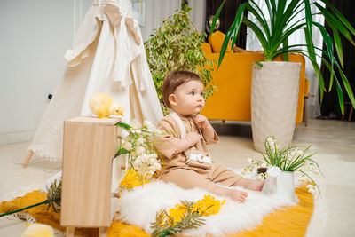 Baby playing at home on the floor tent and flowers spring