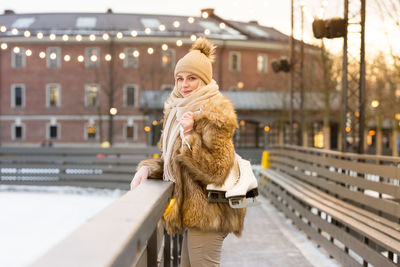 Portrait of woman with ice skates standing on footbridge