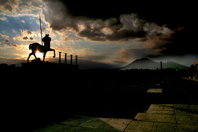 Silhouette people on mountain against sky during sunset