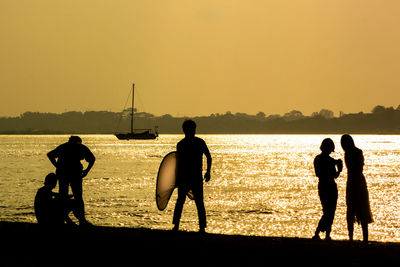 Silhouette people at beach against clear sky during sunset