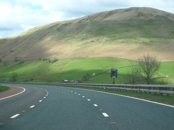 Road leading towards mountains against sky