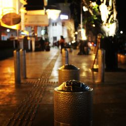 Illuminated street light on footpath by building at night