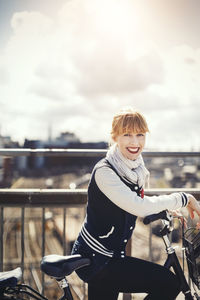 Man riding bicycle on railing against sky