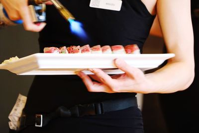 Midsection of woman with  sushi plate