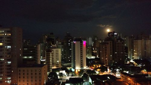 Illuminated buildings in city against sky at night