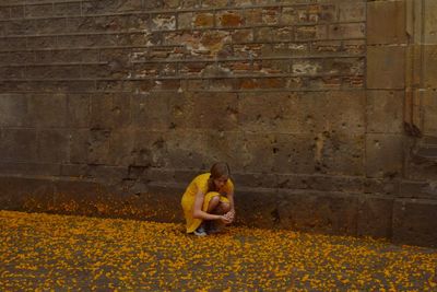 Young woman picking flowers while crouching on footpath