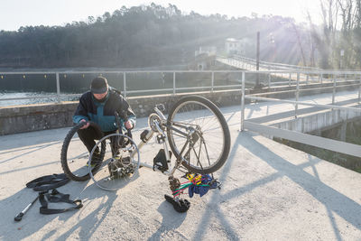 Man repairing bicycle on footbridge during winter