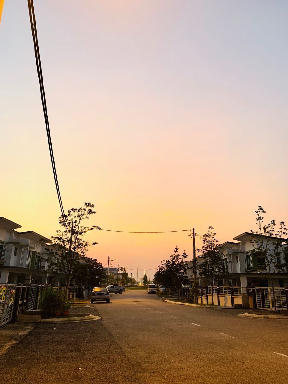 ROAD AMIDST BUILDINGS AGAINST SKY DURING SUNSET