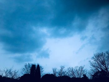 Low angle view of silhouette trees against blue sky