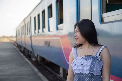 Smiling young woman standing by train