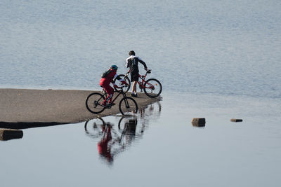 People riding bicycle by lake