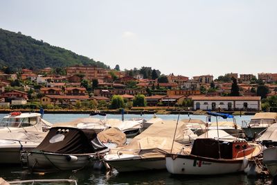 Boats moored at harbor against sky in city