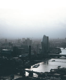 Buildings by river in city against sky