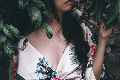 Mid section of a woman in floral dress against tropical leaves