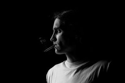 Man smoking cigarette against black background