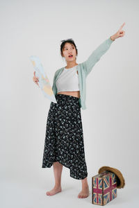 Portrait of young woman standing against white background