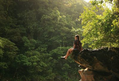 Woman sitting on rock in forest