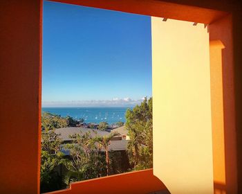 Scenic view of sea against clear blue sky seen through window