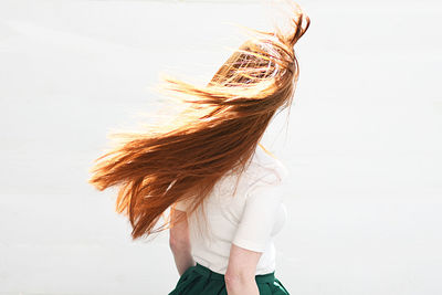 Rear view of woman with brown hair standing against white background