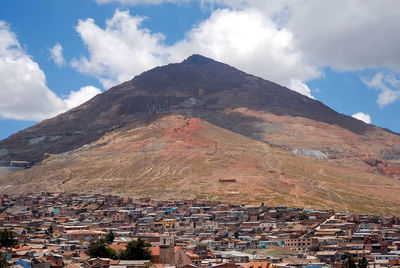 Aerial view of townscape by mountain against sky