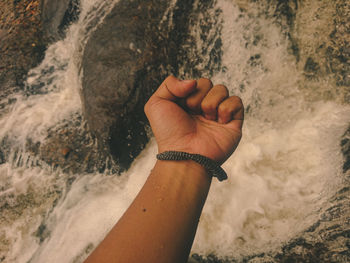 High angle view of wrist over flowing water at stream