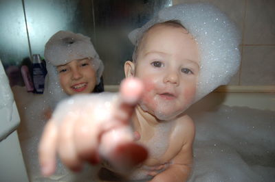 Smiling siblings taking bath in tub at home