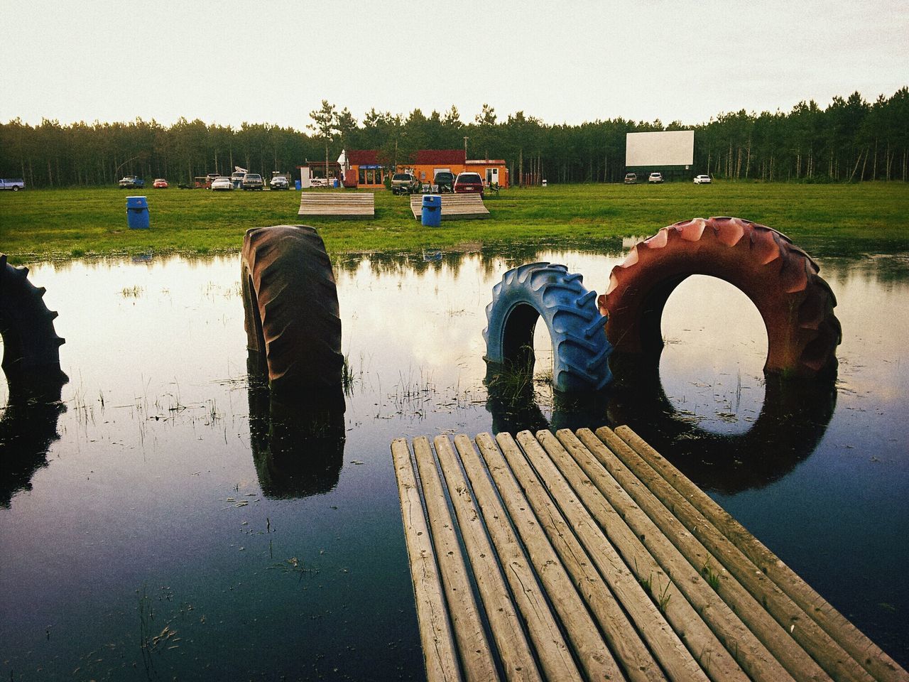 water, tranquility, reflection, lake, grass, field, wood - material, tranquil scene, tree, sky, nature, landscape, circle, no people, outdoors, river, rural scene, wooden, day, clear sky