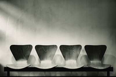 Close-up of empty chairs on table against wall