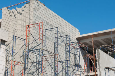 Low angle view of building under construction against clear blue sky