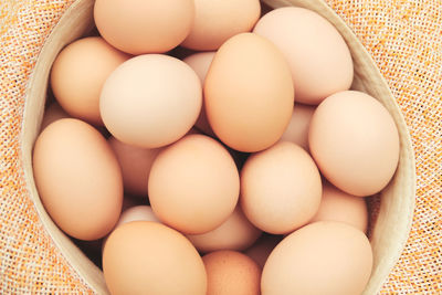 Eggs in straw hat on grass background. chicken eggs in wooden basket on green nature floor at cloudy