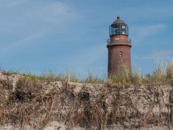 Lighthouse on field against sky