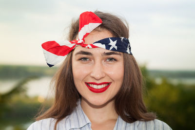 Close-up portrait of beautiful woman smiling while wearing bandana against sky