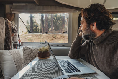 Man with laptop sitting in camping van