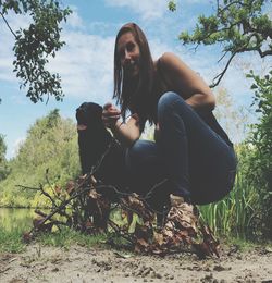 Portrait of young woman sitting on grass against trees