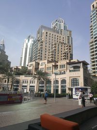 People on street by buildings against sky in city