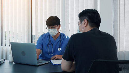 Patient and doctor wearing mask having discussion at clinic