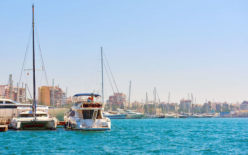 Boats moored at harbor against clear sky