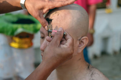 Cropped hands of barber shaving man head