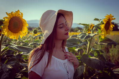 Close-up of woman standing by yellow flowers on field