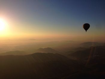 Scenic view of hot air balloon over mountain range during sunset