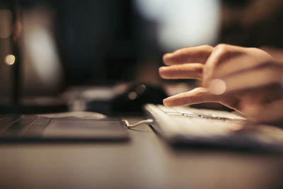 Cropped image of businesswoman using computer keyboard at desk in office