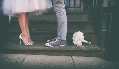 Low section of married couple with white bouquet