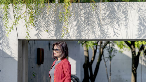 Portrait of woman wearing sunglasses standing against plants