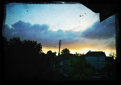 Silhouette of house against cloudy sky