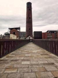 Walkway in city against sky