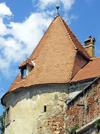 Low angle view of abandoned house in town against sky